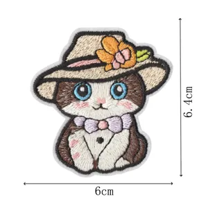 Vue détaillée du joli patch de broderie de chat avec des coutures fines, chapeau et nœud.