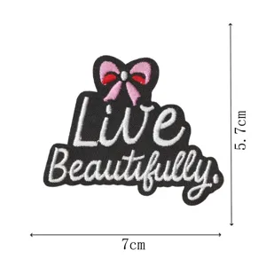 Detaillierter bestickter Aufnäher mit Live Beautifully Schriftzug und rosafarbener Schleife.