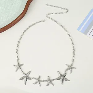 Gros plan sur la chaine de taille en argent avec des pendentifs etoile de mer et maillons fins.