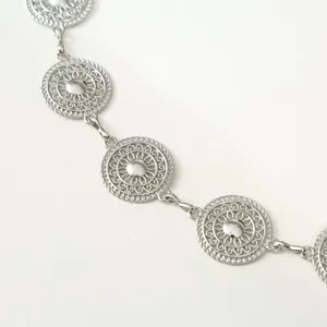 Detailed view of vintage silver metal waist chain with intricate hollow circular pattern links.