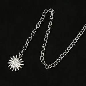 Gros plan détail de la chaîne de corps pendentif soleil argenté, accessoire de taille en métal.