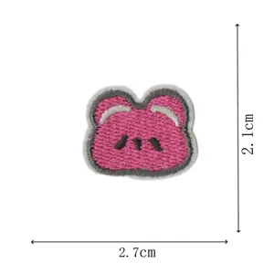 Détail de patch brodé d'ours de dessin animé rose, gros plan d'accessoire de vêtement miniature.