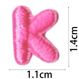 Close up of pink embroidered letter K patch, mini DIY clothing accessory detail view.