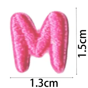 Detailed view of a cute pink embroidered letter M patch, mini DIY clothing accessory.