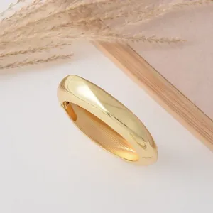 Close-up of a luxurious chunky gold dome bangle bracelet, elegant minimalist teardrop open design.