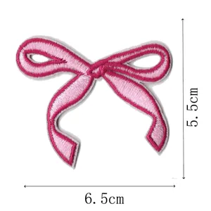Close-up of pink embroidered bow patch detail, showing fine texture and stitching craftsmanship.