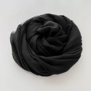 Dettaglio di sciarpa in cotone lino nero che mostra la trama del tessuto e forma arrotolata.