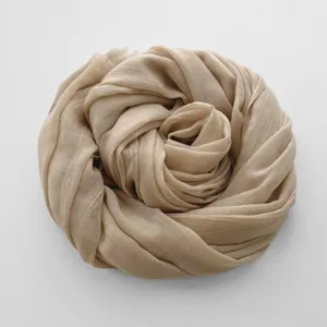 Primo piano di una morbida sciarpa beige in cotone e lino, mostra trama fine e tono caldo.