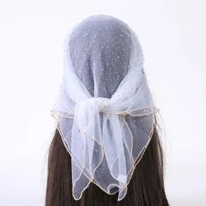 Detailopname van glinsterende strass-hoofddoek van gaas met delicate gouden rand.