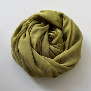 Dettaglio sciarpa in cotone e lino verde oliva, consistenza morbida e accessorio invernale per donne.