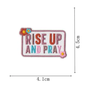 Embroidered patch detail showing religious quote design with colorful floral accents and size markers.