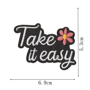 Schwarzer gestickter Flicken mit Take it easy Schriftzug und rosa Blume zur Dekoration.