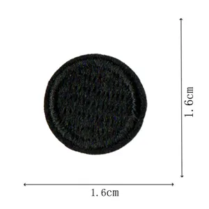 Round black embroidered patch detail, dog tooth edge clothing repair badge close up view.