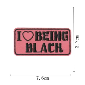 Embroidered patch featuring pink background and black typography with heart symbol detail.