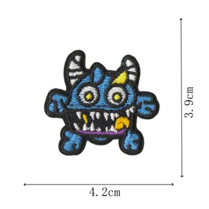 Detalle de primer plano de un parche bordado de monstruo azul divertido con cuernos y dientes.