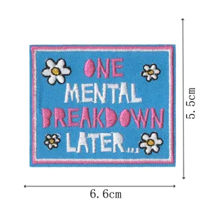 Detailed view of blue embroidered patch with funny English text and white daisy flowers.