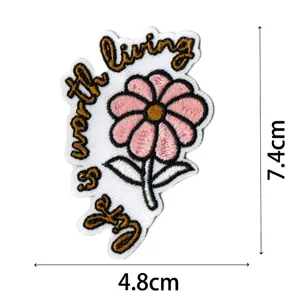 Dettaglio di patch ricamata con motivo floreale rosa e scritta di citazione motivazionale.