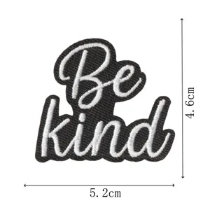 Vista de cerca detallada de un parche bordado en blanco y negro con la frase Be kind.