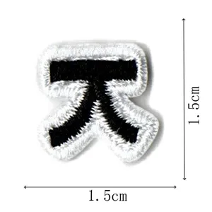 Closeup view showing details of a small black and white embroidered patch, measuring 1.5cm.