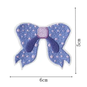 Detailed view of blue embroidered bow patch with polka dots and purple center, measuring 5x6 cm.