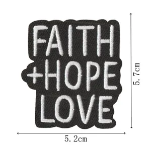 Vista detallada del parche bordado faith hope love, diseño de insignia con letras en blanco y negro.