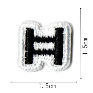 Detail view of black and white embroidered letter patch accessory, compact 1.5cm size.