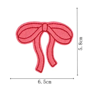 Close up view of pink embroidered bow patch, detailed stitching, clothing repair accessory.