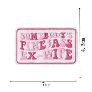Embroidered patch detail view featuring pink text letter design, measuring 7cm by 4.3cm.