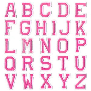 Gros plan sur les écussons de broderie de lettres roses, détail des badges alphabet DIY.