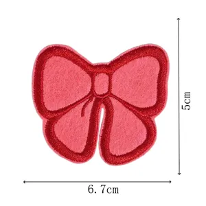 Detailed view of the red embroidered bow patch showing fine stitching texture and size.