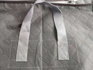 Close-up detail of grey non-woven storage bag handle and transparent window, durable design.
