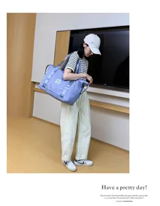 Detailaufnahme einer großen hellblauen Reisetasche, die von einem Model getragen wird.