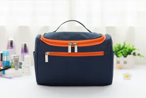 Detailansicht der großen dunkelblauen Kosmetiktasche mit leuchtend orangen Reißverschlüssen.