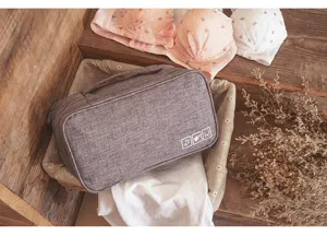 Detail view of a portable grey fabric travel underwear storage bag in a cozy setting.