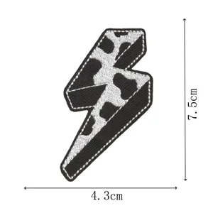 Close-up detail of the black and white cow print lightning bolt embroidered patch with clear edges.