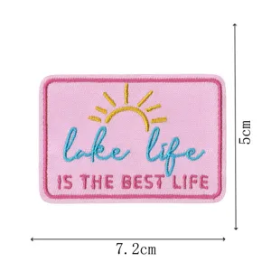 Vue détaillée d'un patch brodé rose avec soleil et texte, idéal pour loisirs créatifs.