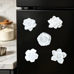 Close-up detail of 3D white flower refrigerator magnets attached to a black fridge surface.