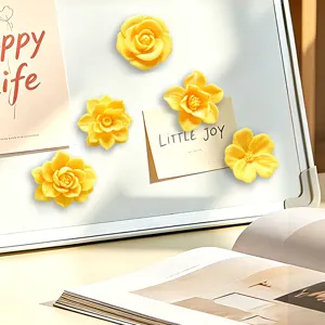 Close-up detail of 3D yellow flower fridge magnets on a white board with decorative notes.