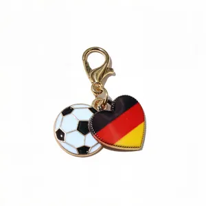 Close-up detail of a metal alloy football and German flag heart charm with gold lobster clasp.