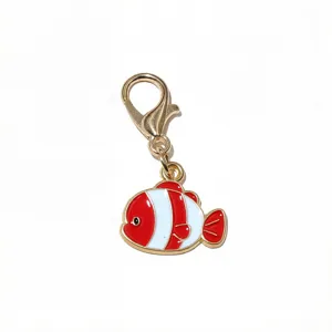 Vue de détail d'un petit pendentif poisson en émail doré avec fermoir mousqueton DIY.