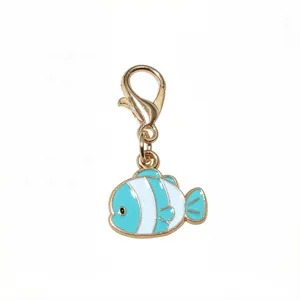 Gros plan détaillé d'un charmant pendentif poisson en émail bleu et blanc avec mousqueton doré.
