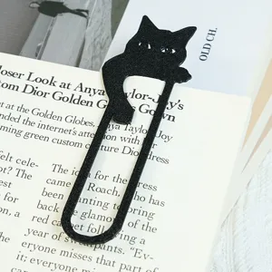 Nahaufnahme des niedlichen schwarzen Katzen Metalllesezeichens auf offener Buchseite.