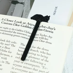 Detailansicht eines schwarzen 3D-gedruckten Katzen-Lesezeichens auf einem offenen Buch, perfekt.