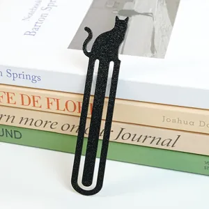 Detailansicht eines eleganten schwarzen Katzen Lesezeichens auf dekorativem Buchstapel.