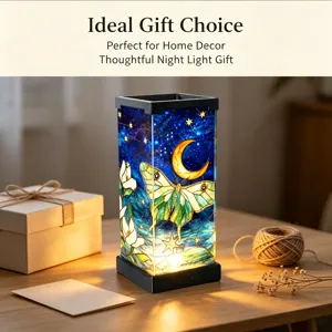 Dettaglio della lampada da notte in vetro colorato con cielo stellato e falena su tavolo con regalo.