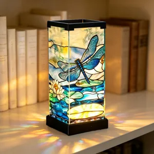 Lampada notturna in vetro colorato con motivo di libellula blu e ninfea sulla scrivania.