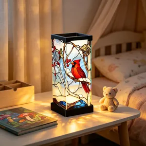 Dettaglio di una lampada da notte in vetro colorato con un uccello cardinale rosso sul tavolo.