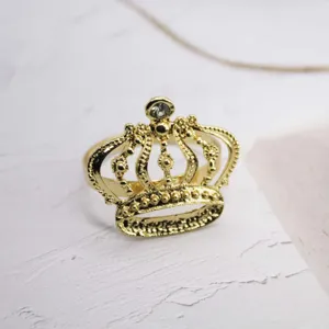 Primo piano dettagliato dell'elegante portatovagliolo a corona dorata con strass trasparente.