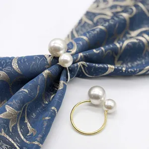 Close-up detail of double pearl napkin ring, elegant metallic ring and shiny pearl decor.