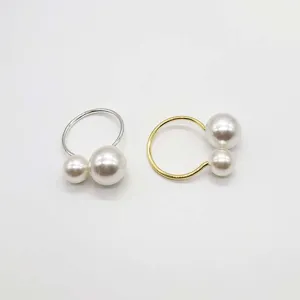 Close up detail of elegant pearl napkin rings featuring shiny pearls and gold silver metal bands.